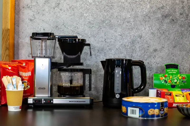 En benk med vannkoker, Moccamaster, te, kaffe og te kjeks