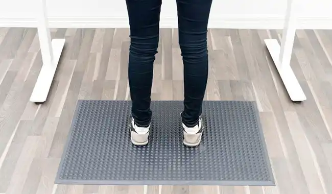 Person som står ved pult på en ergonomisk matte