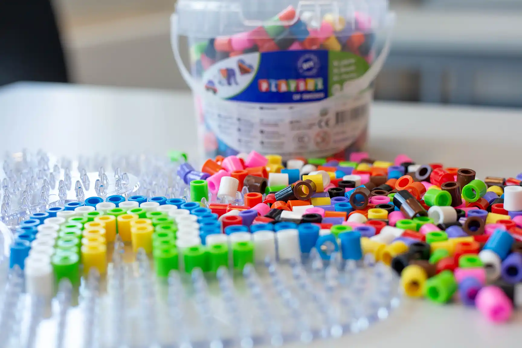 Perler på perlebrett og en liten bøtte med perler